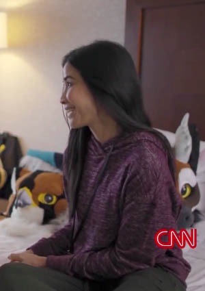 Journalist Lisa Ling sits on a bed, surrounded by fursuit heads.