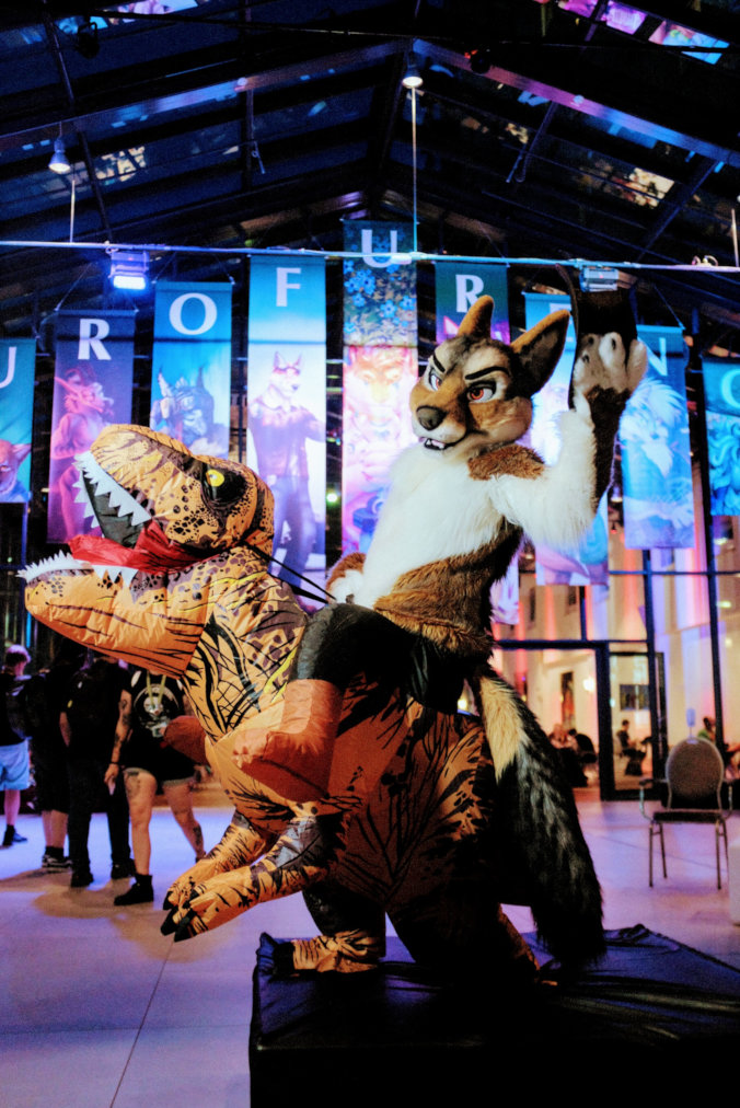 Fursuiter riding an inflatable Tyrannosaurus rex at Eurofurence 25; photo by Alex 'Khaki' Vance